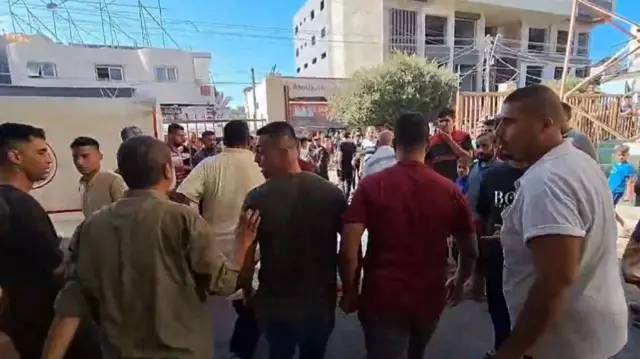 Men walk through the streets after a body is unloaded from an ambulance