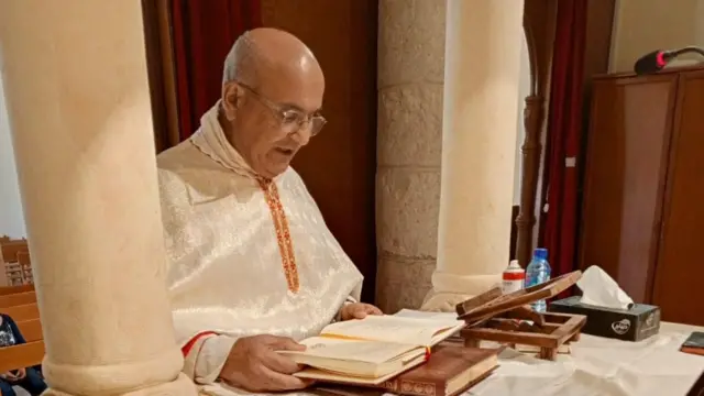 A priest sitting in garments reading