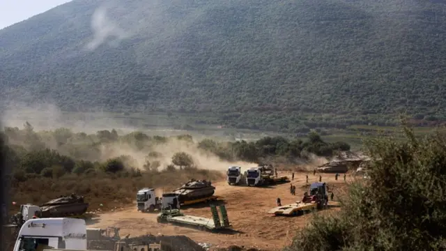 A landscape view of hills in the background and an Israeli tank being moved