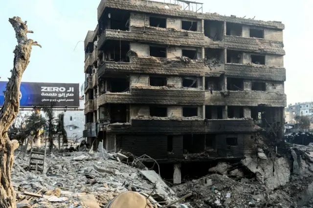 A destroyed building sits near a crater
