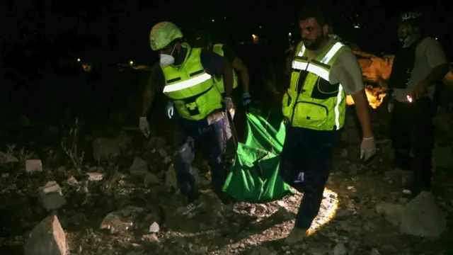 Rescuers evacuate a body pulled from the rubble of a Civil Defence emergency center