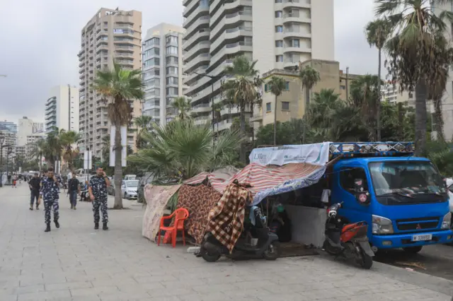 Lebanese security forces members check on displaced people who set up makeshift shelters on Beirut's seaside promenade