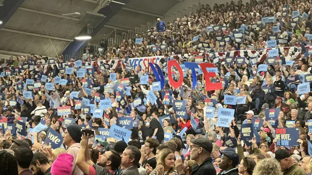 Crowds hold up 'Harris Walz' signs as tey wait for Obama to take the stage