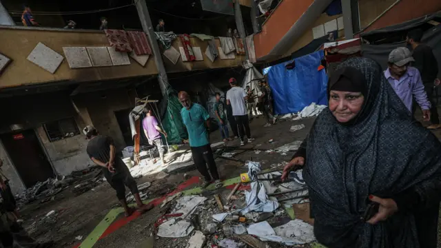 Displaced Palestinians inspect damage inside Rafida school, sheltering people, following attack