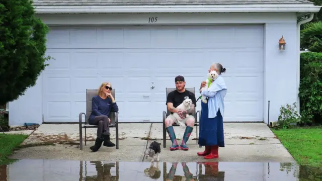 Residents sit in their driveway on a street that was flooded by rains from Hurricane Milton on October 10, 2024 in Altamonte Springs, Florida