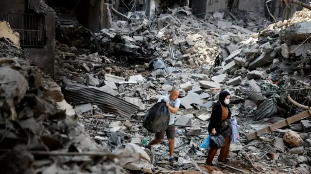 People walk at the site of an Israeli air strike, amid ongoing hostilities between Hezbollah and Israeli forces, in Beirut, Lebanon, October 11, 2024.