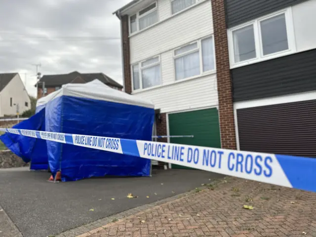 Police tape and a tent in front of the McCullough family home, which is three-storey.