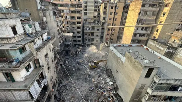 Search and rescue team members try to find victims in the debris of a damaged building after an Israeli military strike on the Basta neighborhood in Beirut