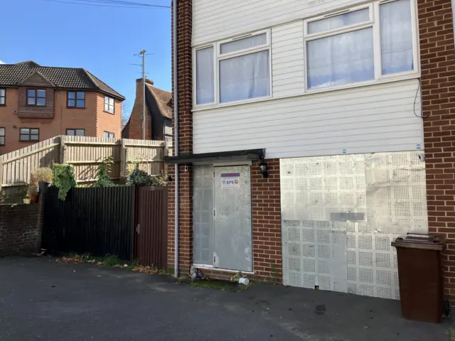 The three-storey property on Pump Hill. It has metal grilles covering the front door and windows.