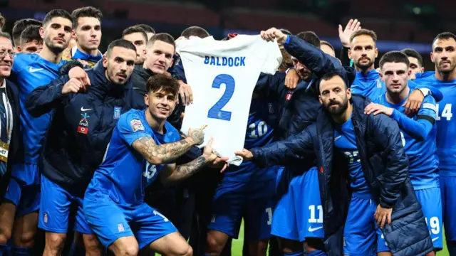 Greece players hold up a shirt bearing George Baldock's name and number after their victory over England during the UEFA Nations League 2024/25 League B Group B2 match between England and Greece at Wembley Stadium on October 10, 2024 in London, England.