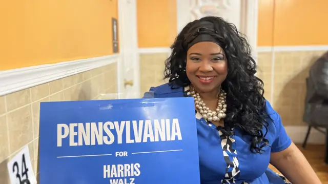 Kari Holmes, a pastor in eastern Pennsylvania, speaks to the BBC from behind a sign which reads "Pennsylvania for Harris and Walz"