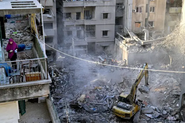 Search and rescue team members try to find victims in the debris of a damaged building after an Israeli military strike on the Basta neighborhood in Beirut, Lebanon,