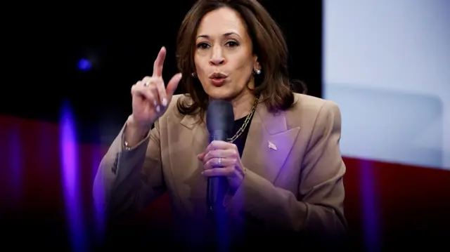 Kamala Harris, wearing a brown suit, talks into a microphone