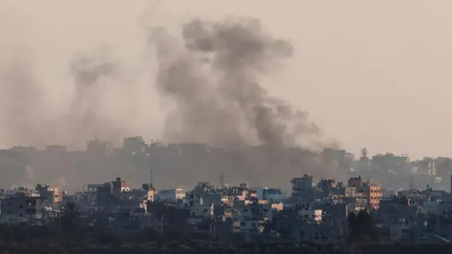 Black smoke rising, with buildings in the foreground and background