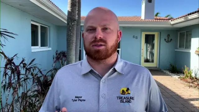 Mayor Tyler Payne of Treasure Island, Florida stands in front of a blue single-level home