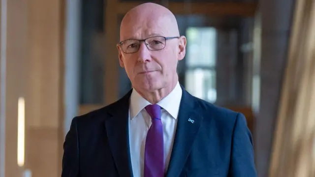 John Swinney wearing a navy-coloured suit and a purple tie