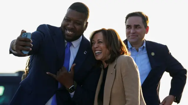 Kamala Harris poses for a selfie with Leonardo Williams, Mayor of Durham, North Carolina, as she arrives at Raleigh Durham International Airport