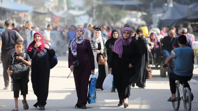 Women and children walking with their belongings in hand.