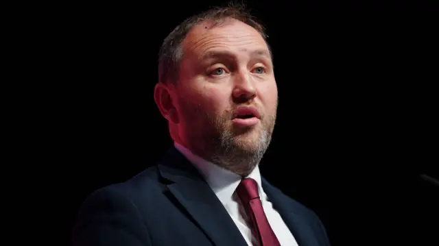 Ian Murray wearing a navy blue suit and red tie