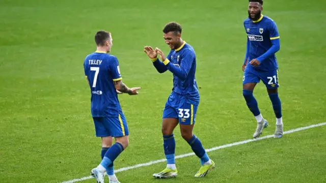 Isaac Ogundere of AFC Wimbledon celebrates scoring his team's third goal with teammate James Tilley