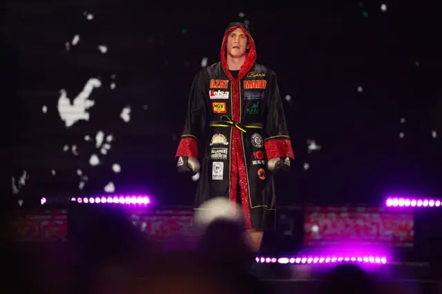 Jack Massey makes his ringwalk dressed in black and red