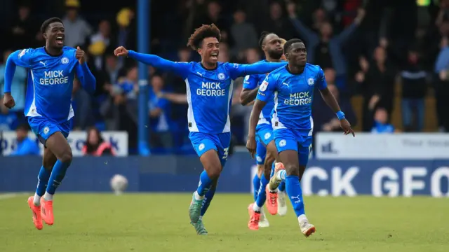 Peterborough United players run along the pitch to celebrate a goal