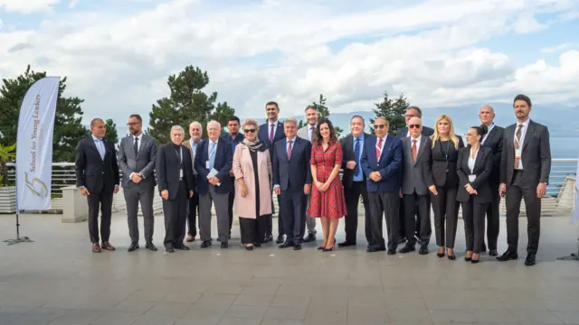 Nineteen people, including Alex Salmond, stand in a row in business-wear posing for a group photo