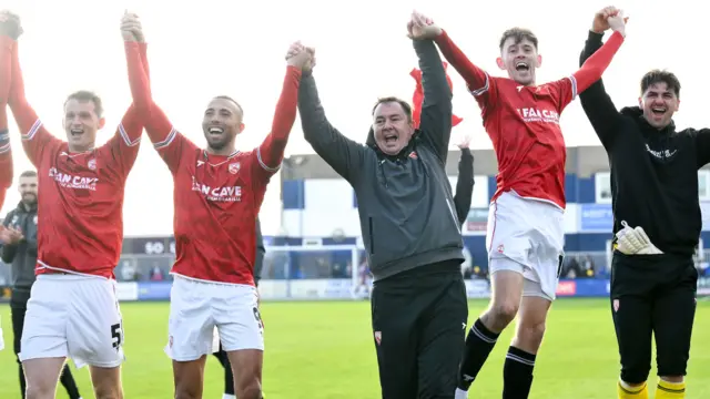 Derek Adams and his Morecambe players celebrate at Barrow