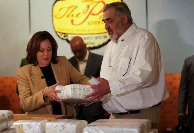 Kamala Harris with a supporter, helping to pack nappies as part of relief efforts