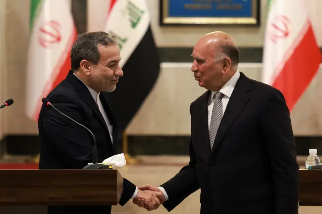 Iran's Foreign Minister Abbas Araqchi shakes hands with his Iraqi counterpart Fuad Hussein