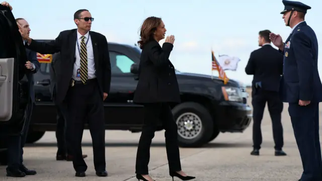 Kamala Harris salutes a military officer as she walks to board Air Force Two