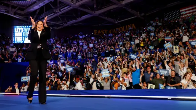 Harris claps as she walks onstage at a rally