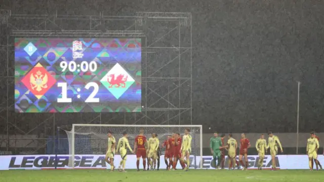 Montenegro v Wales, match action with scoreboard in background