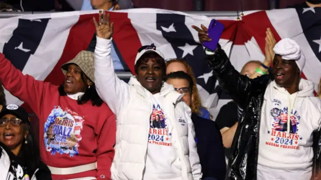 Black women wave at the Harris rally