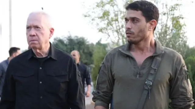 Yoav Gallant walks with a military commander