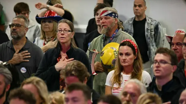 Audience stands for national anthem