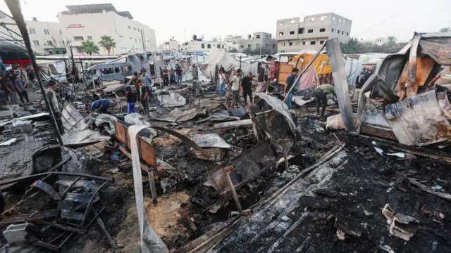 People comb through the charred wreckage of structures at al-Aqsa