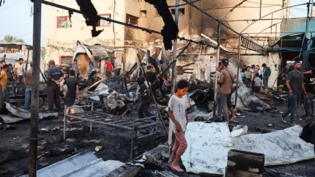 Palestinians survey the damage at the site of an Israeli strike on tents sheltering displaced people at Al-Aqsa Martyrs hospital in Deir Al-Balah in the central Gaza Strip, on October 14, 2024, amid the Israel-Hamas conflict