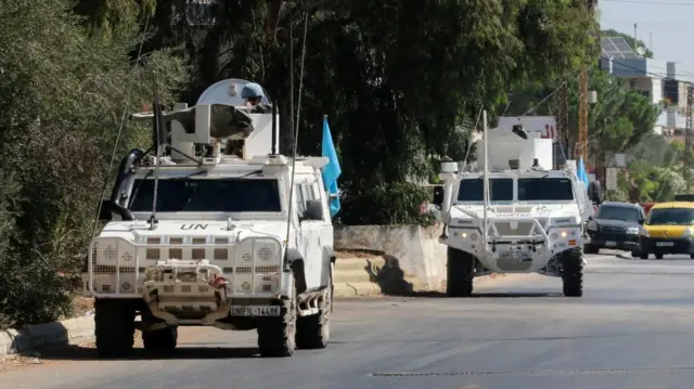 Two white UN vehicles on a road