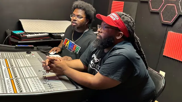 Two men sit at studio mixing board