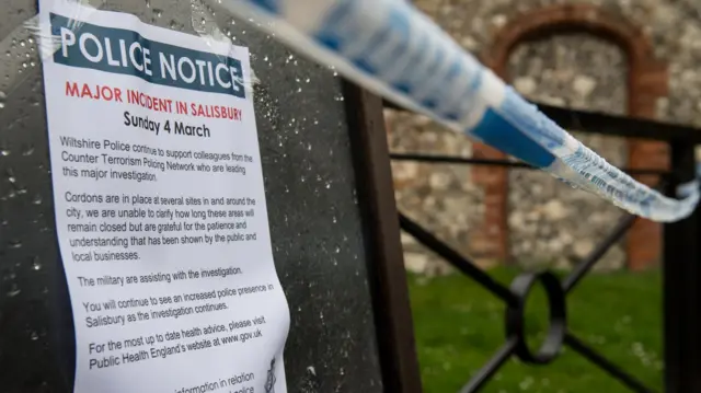 A police warning sign is placed on a bench in Salisbury at the time of the novichok poisonings. There is also blue and white tape visible in the background