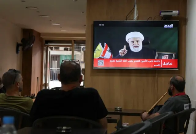 People watch Hezbollah deputy leader Sheikh Naim Qassem delivering a televised address, as they sit in a cafe in Beirut, Lebanon 15 October 2024