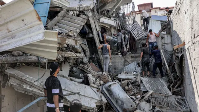 Men work to remove rubble from a badly damaged building