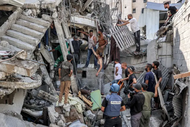 People gather outside a collapsed building as they attempt to extricate a man from underneath the rubble following Israeli bombardment in the Saftawi district in Jabalia in the northern Gaza Strip on October 15, 2024