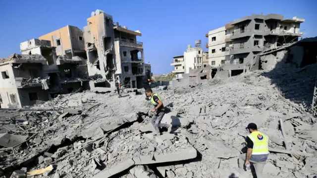 Rescuers search the rubble in aftermath of a series of strikes on Qana in southern Lebanon