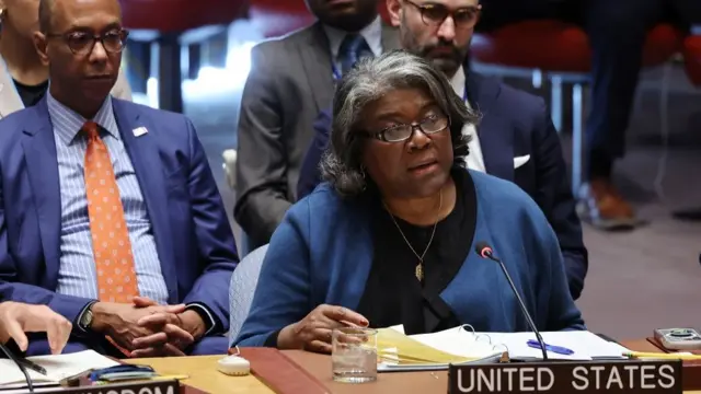 Ambassador Linda Thomas-Greenfield sits and speaks into the microphone at the UN Security Council meeting. She has a sign with UNITED STATES on her desk