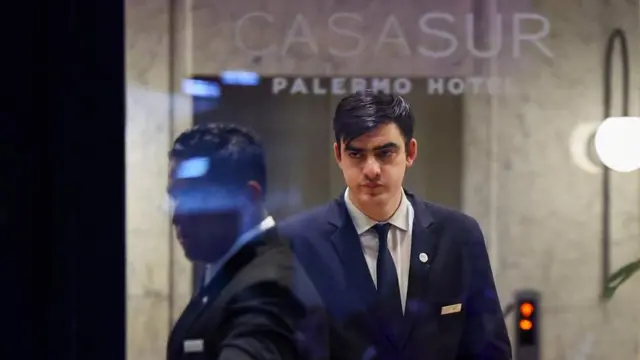 Staff members look on through the front entryway of the hotel