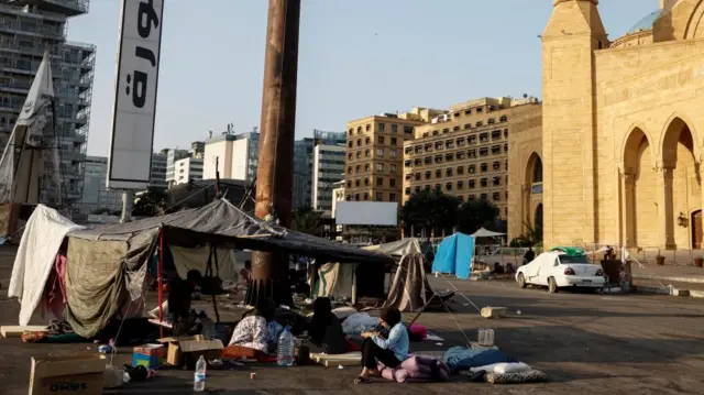 On the central Beirut streets, people sit under makeshift shelters beside a grand building