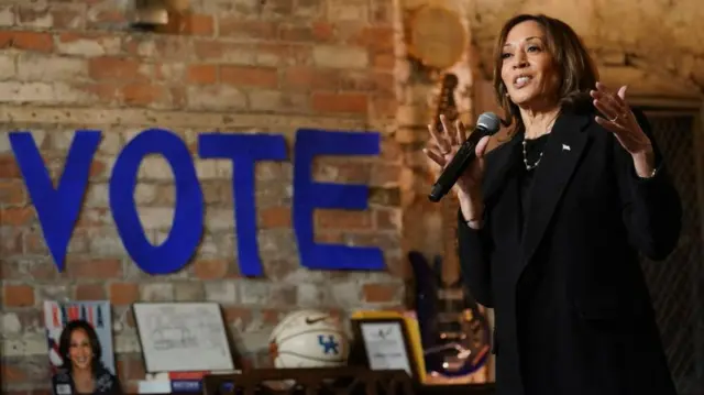 Harris speaks with a large sign saying to vote behind her