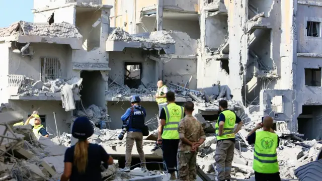 Rescuers search the rubble in aftermath of a series of strikes on Qana in southern Lebanon, with press present